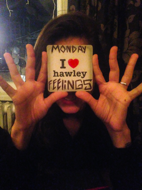 Fernanda holding a I Love Hawley drink coaster writing Monday Feelings on it