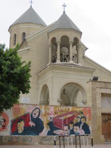 A catholic church with a wall with grafitti showing muslim woman crying