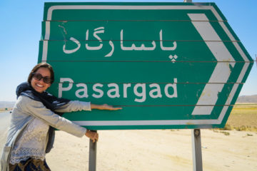 Fernanda segurando a placa de Pasargada na estrada do Irã