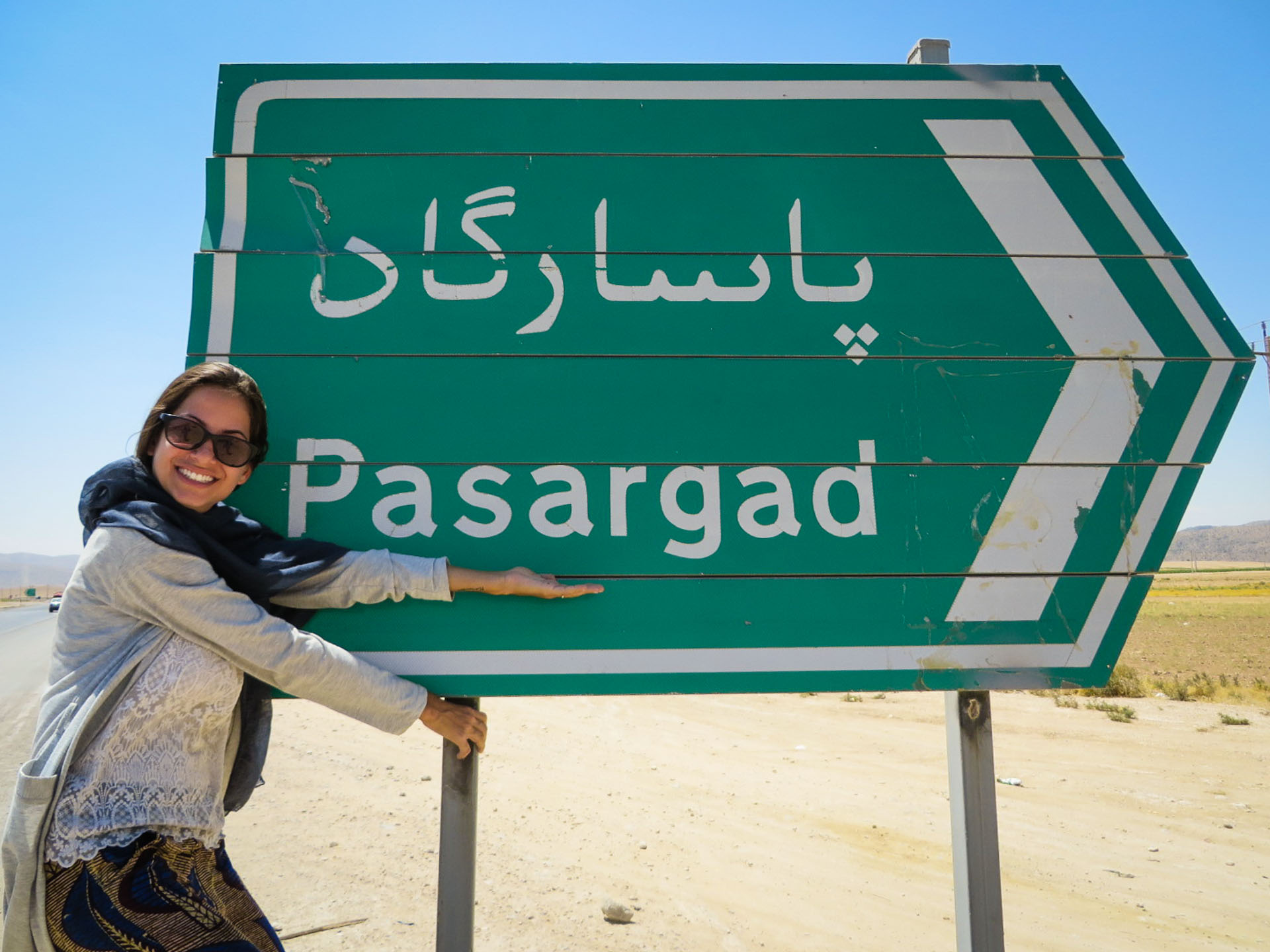 Fernanda segurando a placa de Pasargada na estrada do Irã