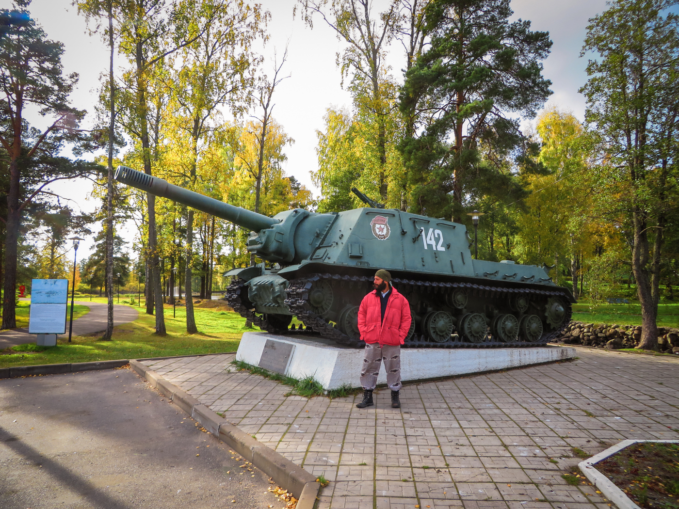 Tiago in front of a world war II tank in a forest in Russia