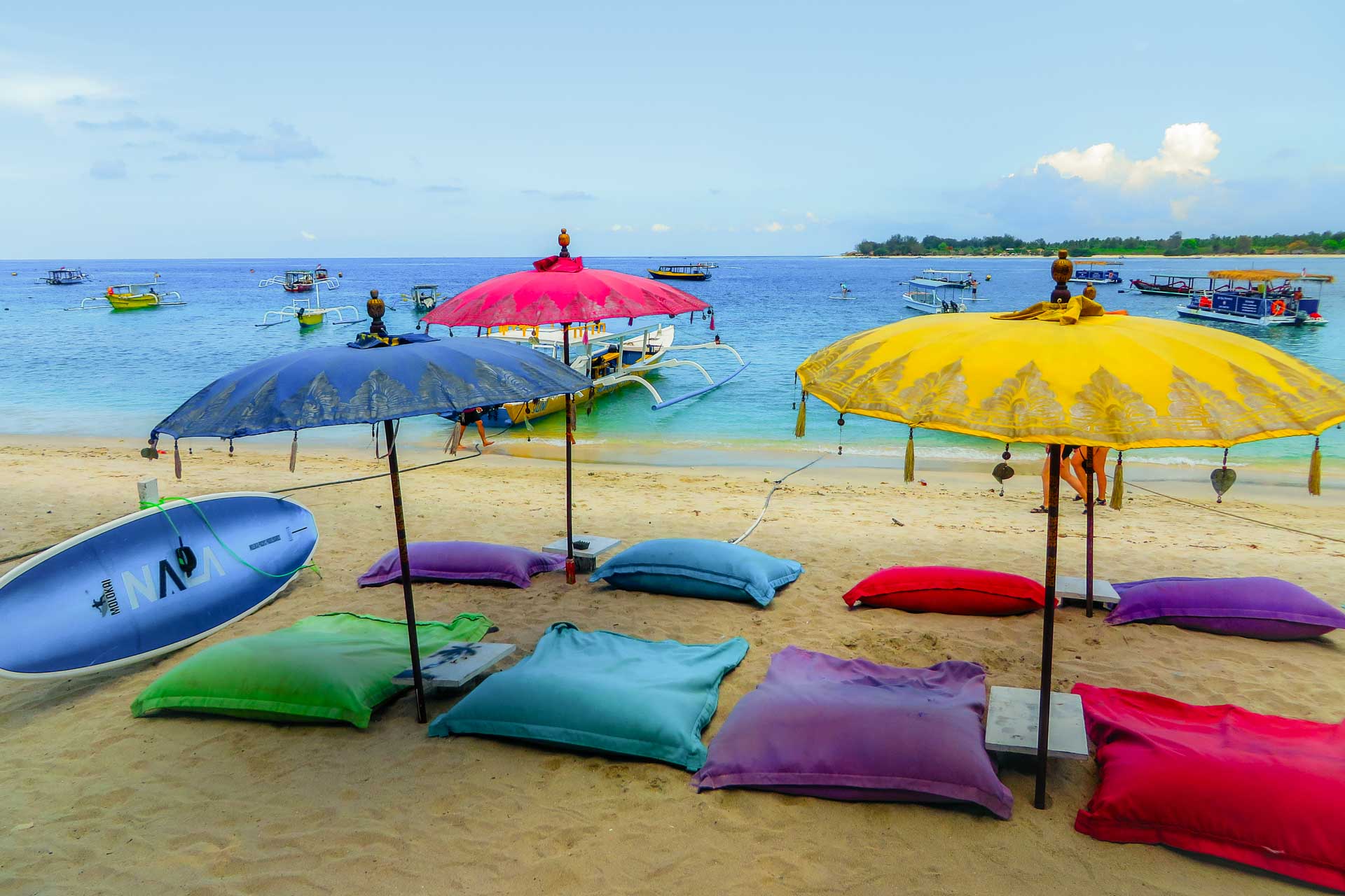 Guarda-sois coloridos e almofadas coloridas na praia de Gili Air