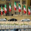 Iranian flags in the city with cars passing by