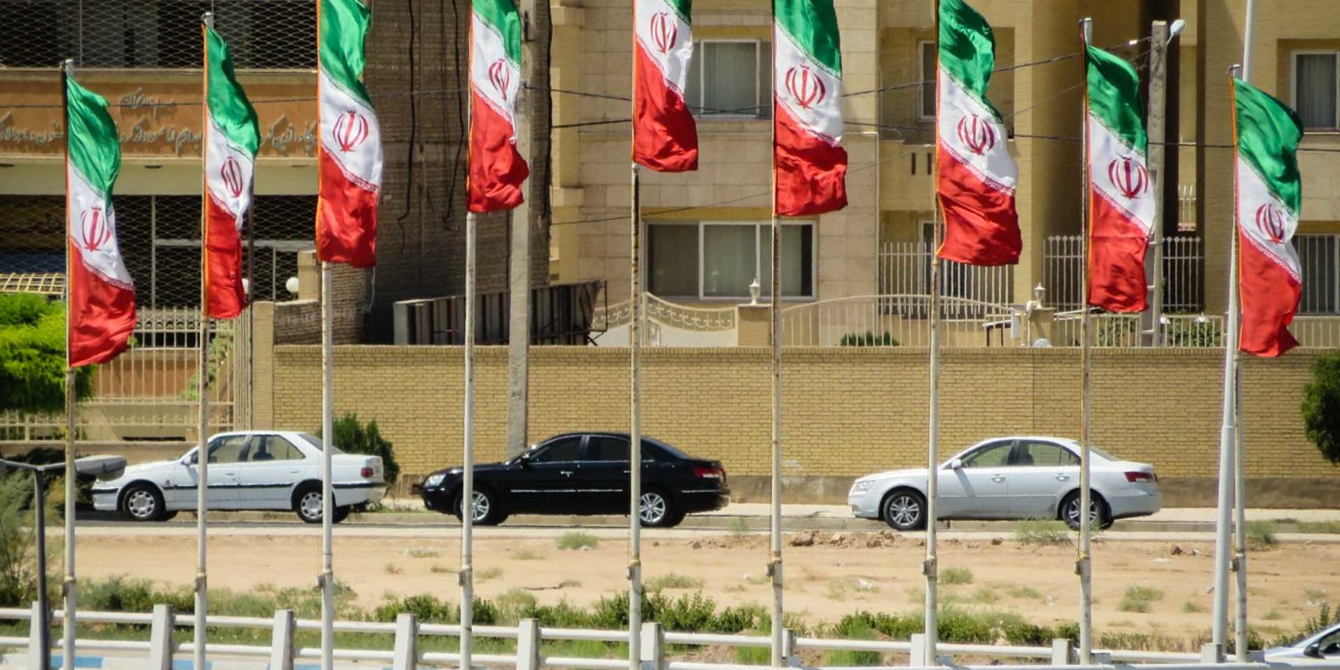 Iranian flags in the city with cars passing by