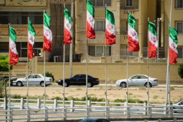 Iranian flags in the city with cars passing by