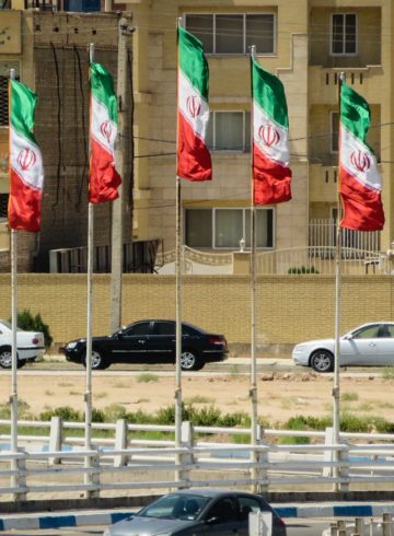 Iranian flags in the city with cars passing by