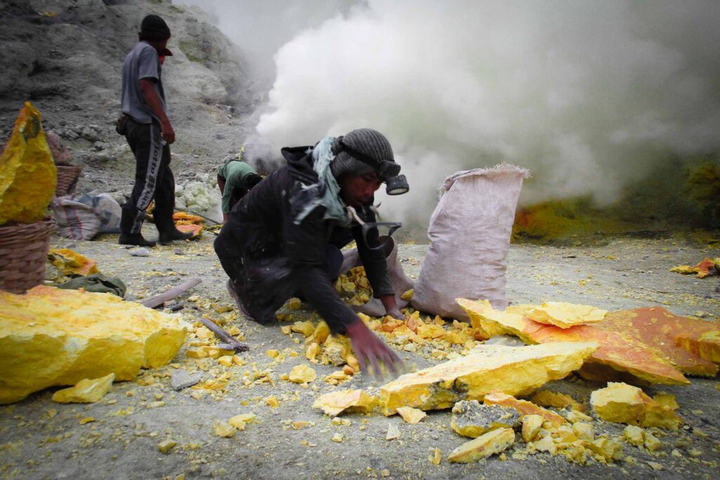 A man without breathing mask working with sulphur in Ijen volcano
