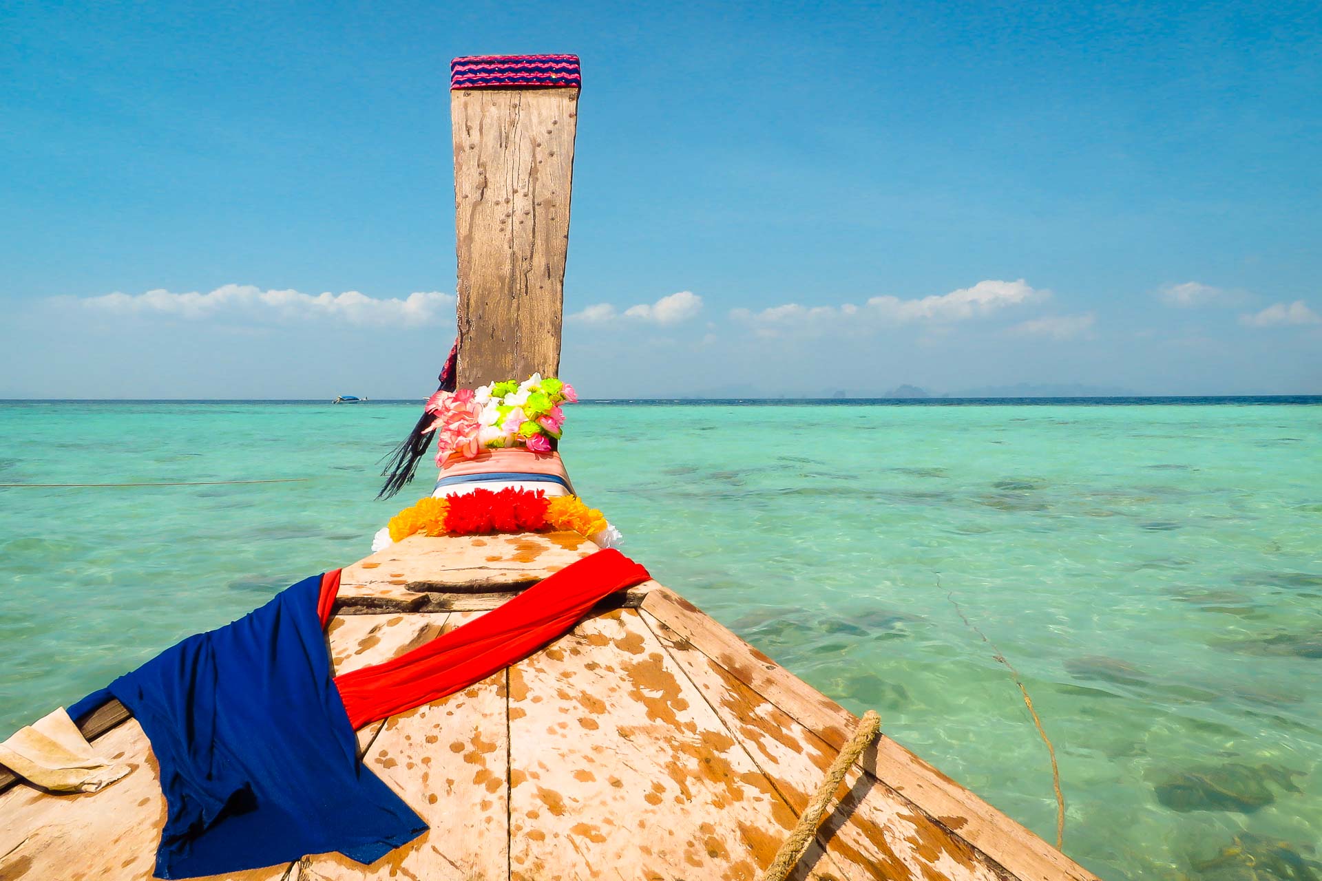 Um barco tailandês colorido em uma água cristalina com panos coloridos sobre ele