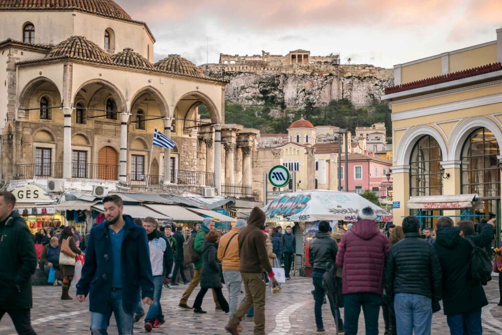 Monastiraki in Greece with a square full of people walking and the Acropolis on top of the mountain in the background