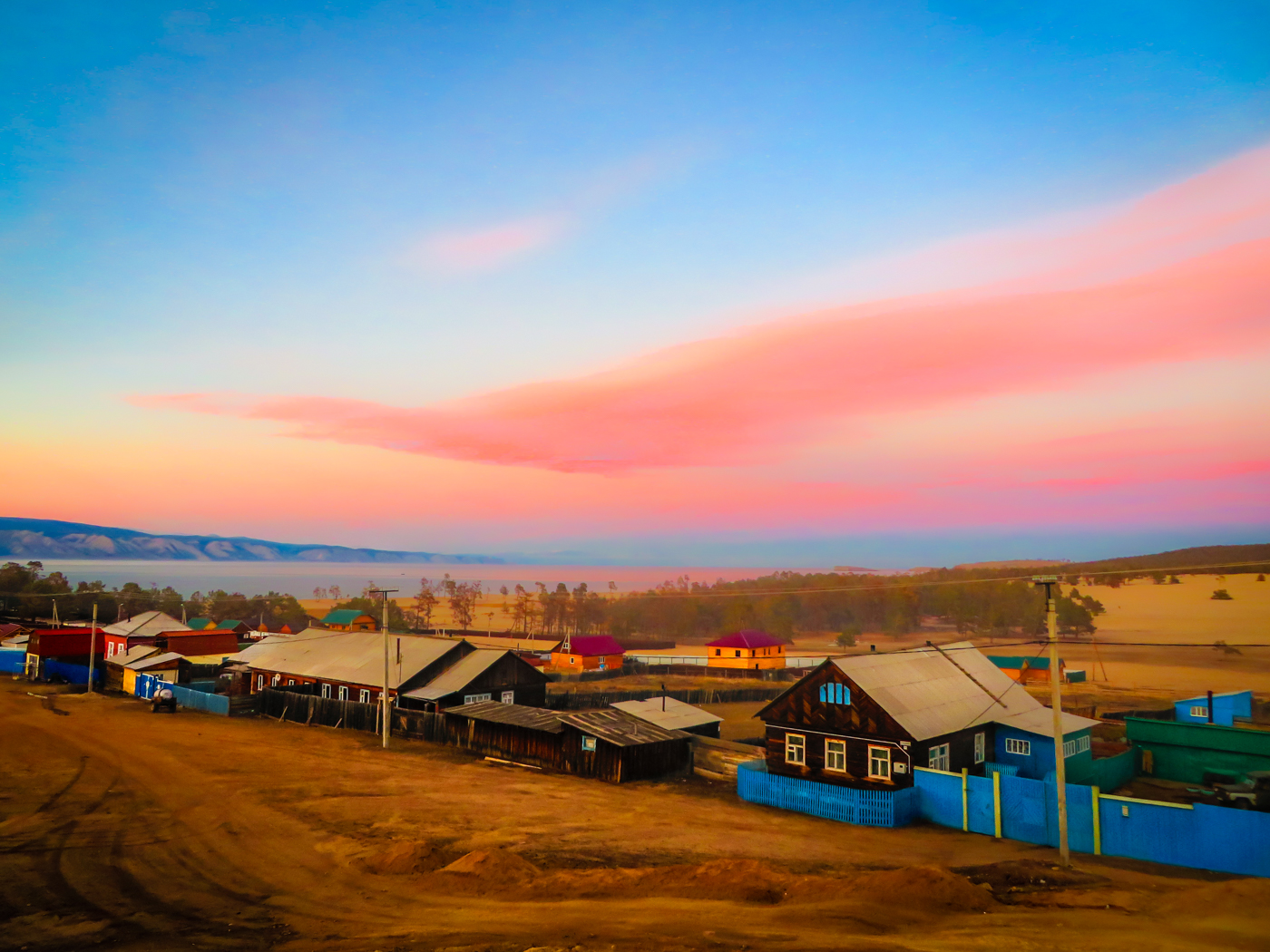 Uma vila tradicional inteira em chão de terra batida em Irkutski na Russia, perto do Lago Baikal, com o céu todo rosa e azul