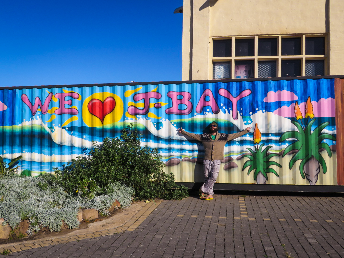 Tiago in front of an art work written We Love J-Bay