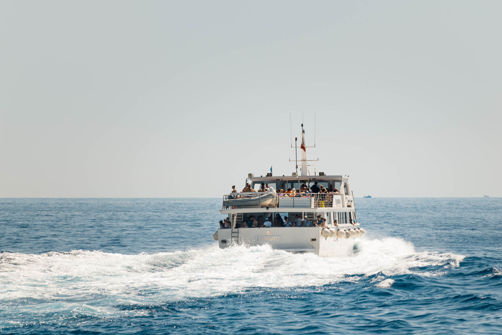 A boat in the ocean alone with people in it going to the cinque terre