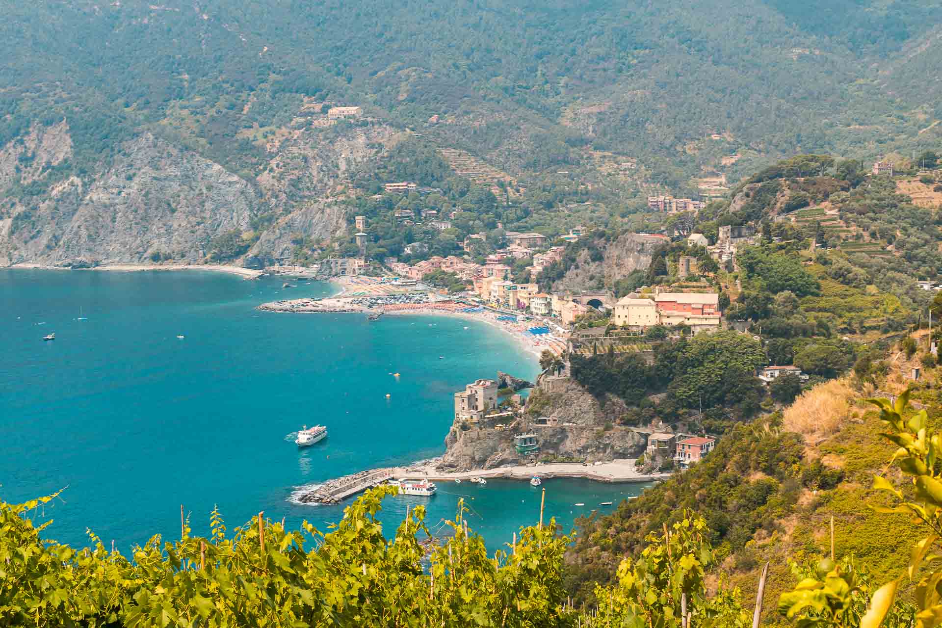 Vista da trilha de Cinque Terre com uma praia ao fundo entre montanhas