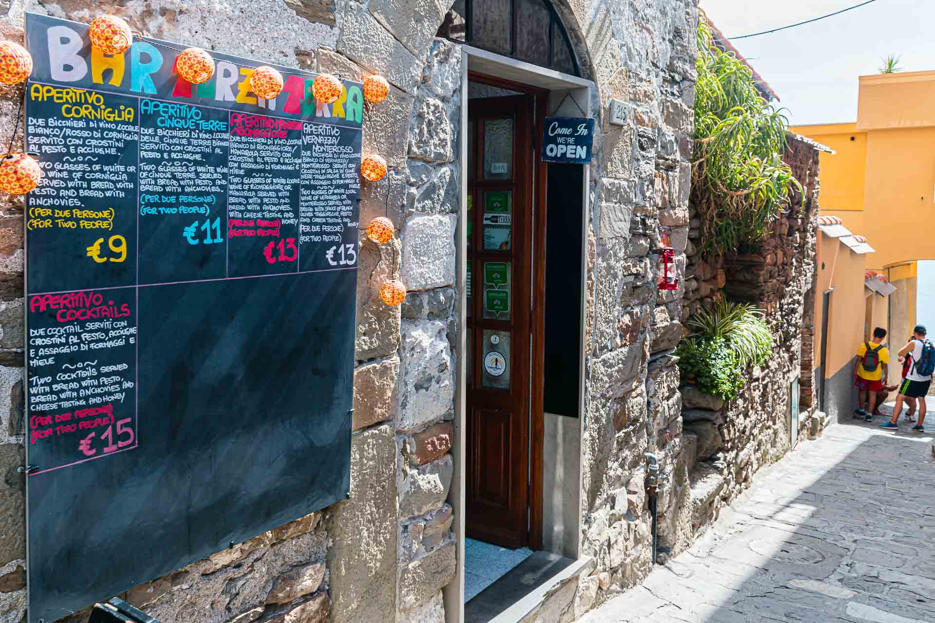 Entrada de um restaurante com um menu na porta e o mar ao fundo