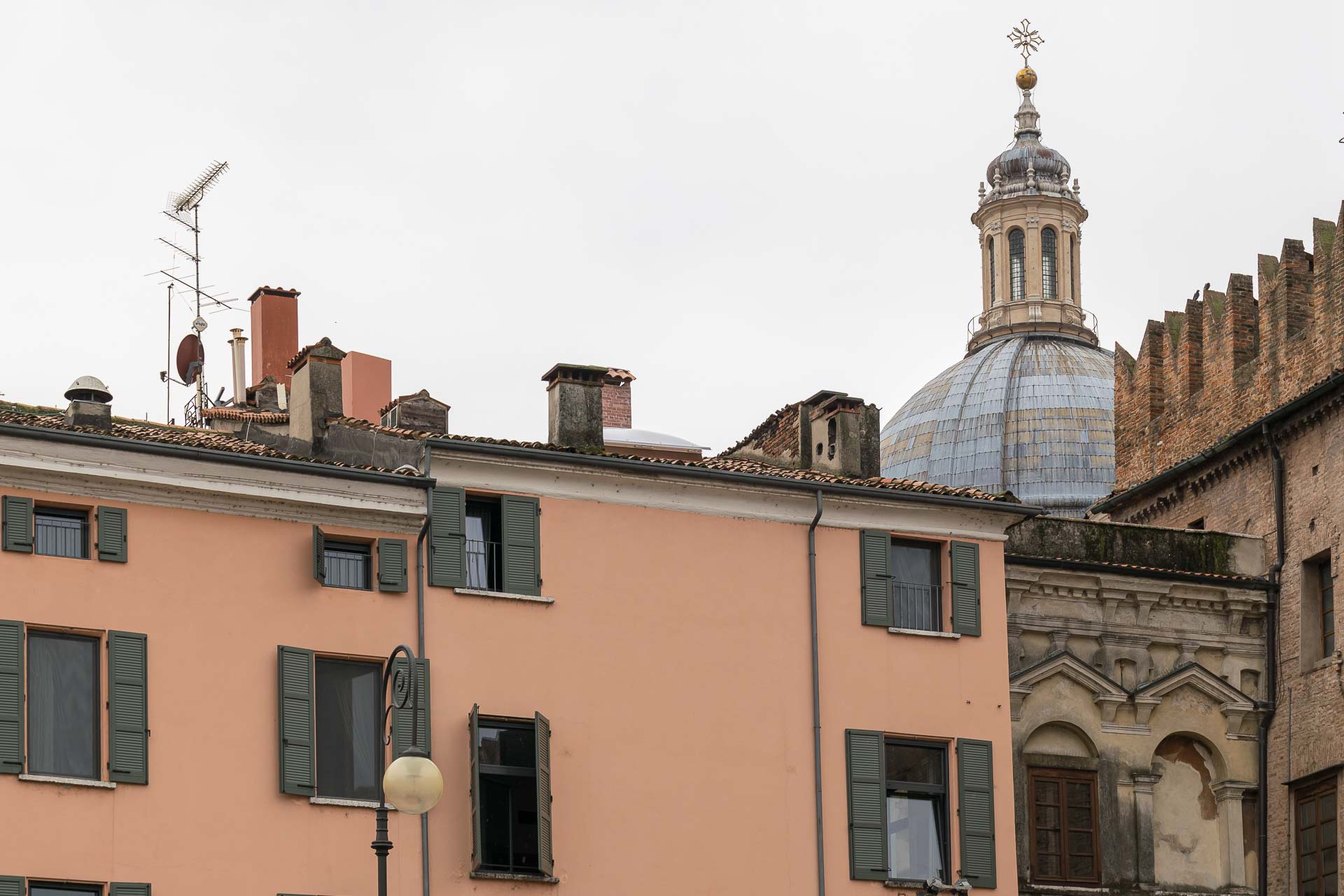 A wall with windows and a dome in the background