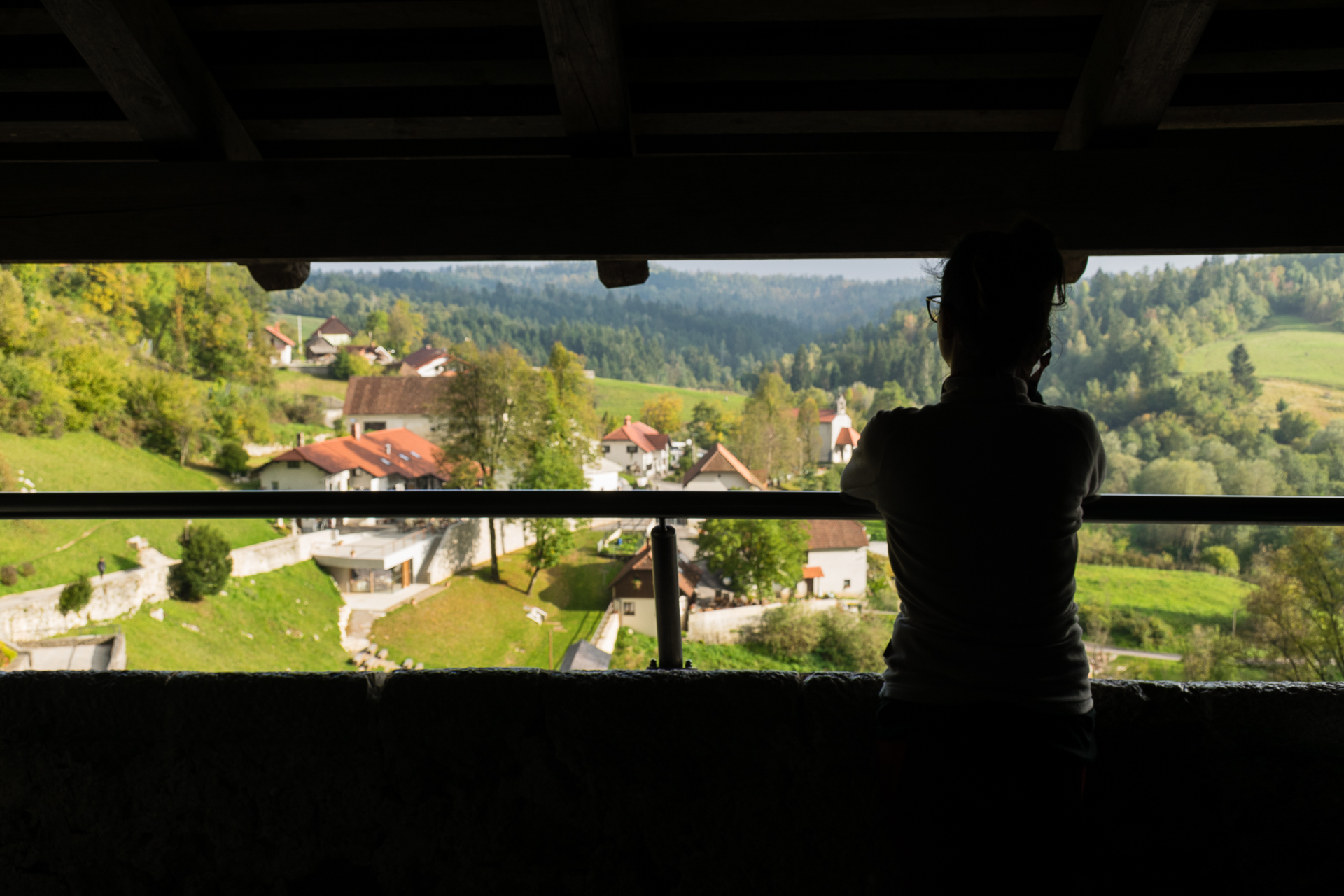 Fernanda em uma das janelas do Castelo de Predjama com a vista de todo o complexo ao fundo