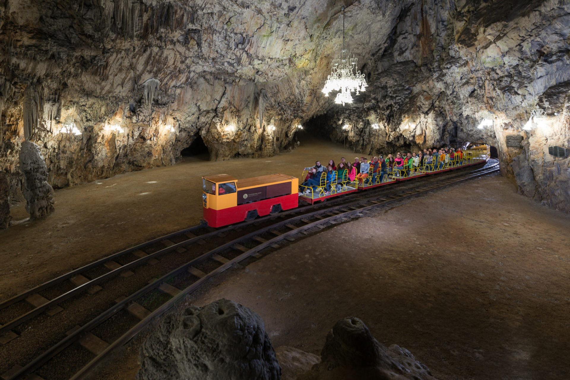 a train on a trail inside Postojna Cave with people in it