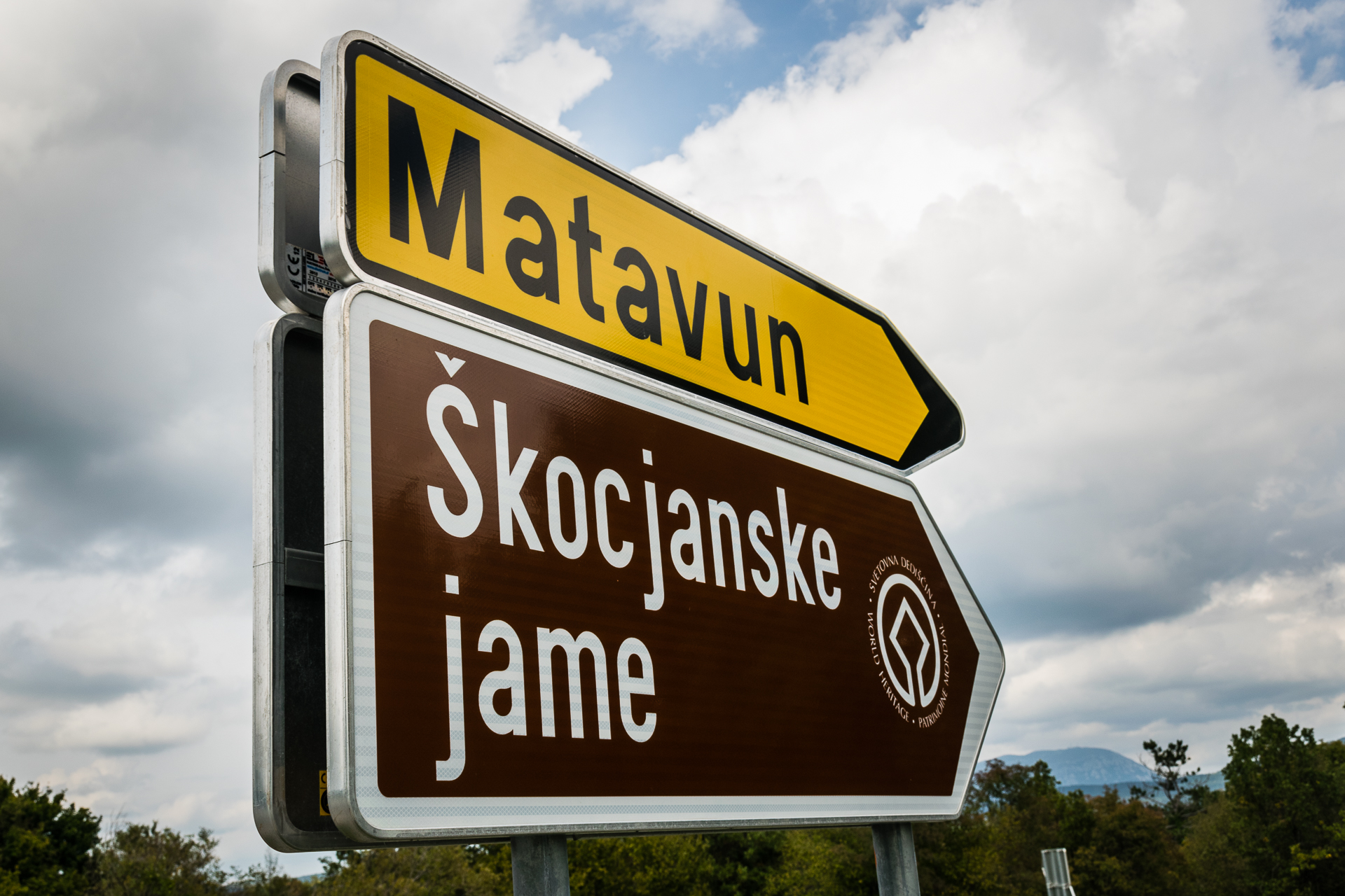 A sign writen Skocjanske Jame and Matavun, which is the directions for Postojna Cave in Slovenia