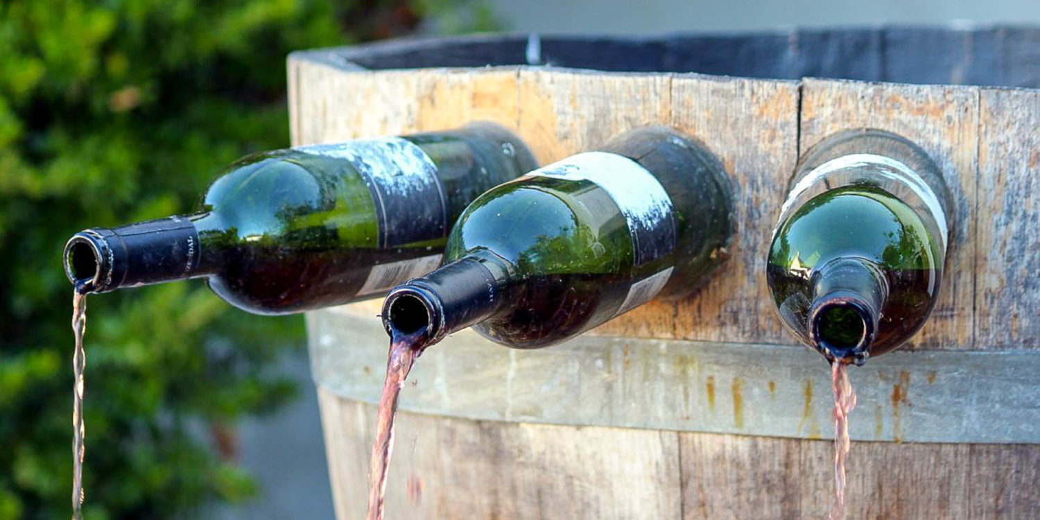 Uma fonte de vinho na Itália de madeira com garrafas presa e saindo vinho