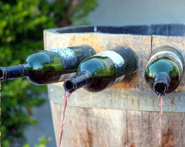 Uma fonte de vinho na Itália de madeira com garrafas presa e saindo vinho