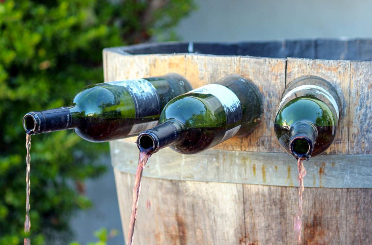 Uma fonte de vinho na Itália de madeira com garrafas presa e saindo vinho