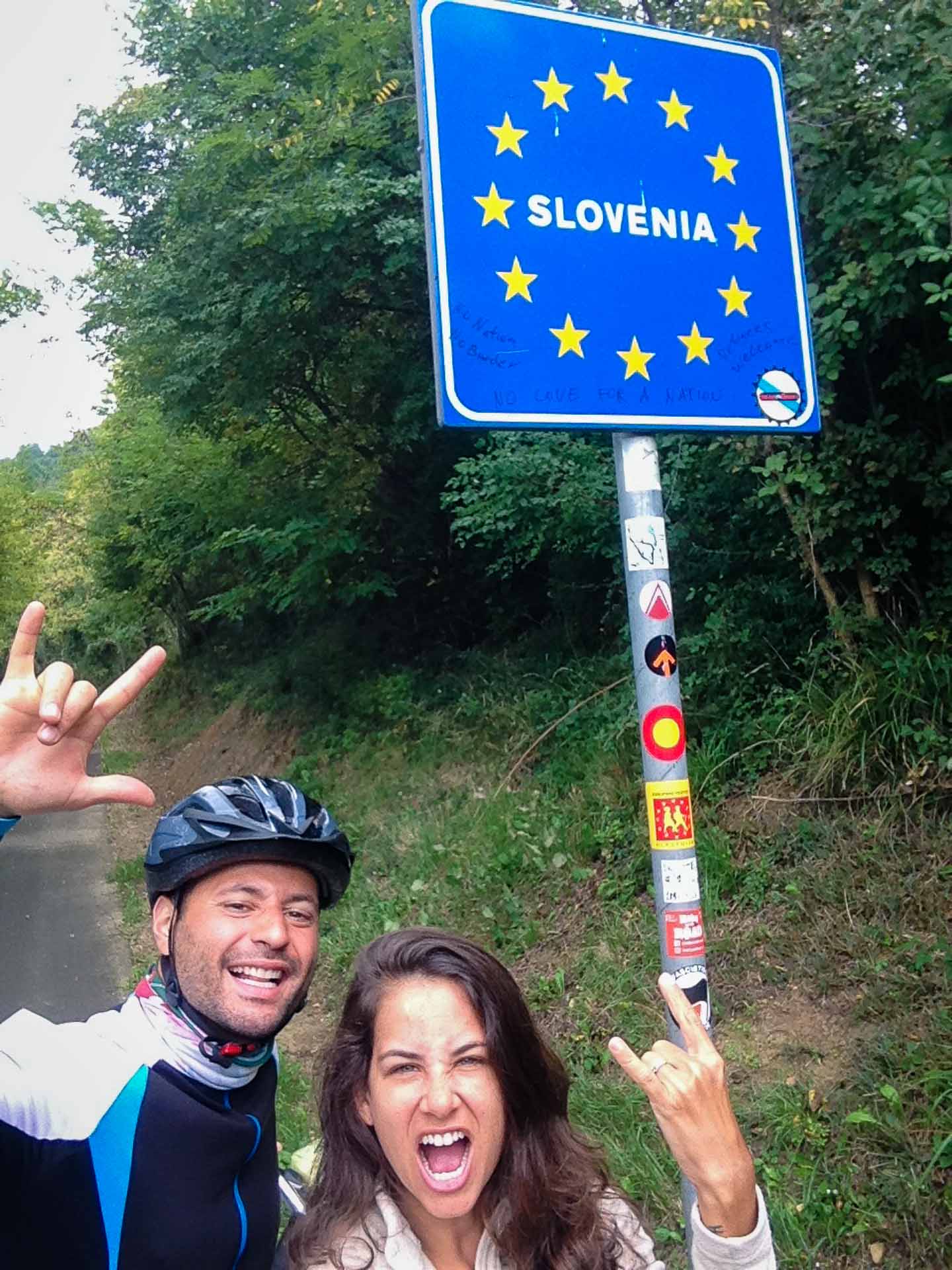 Tiago e Fernanda atravessando a fronteira da Itália para a Eslovênia de bicicleta 