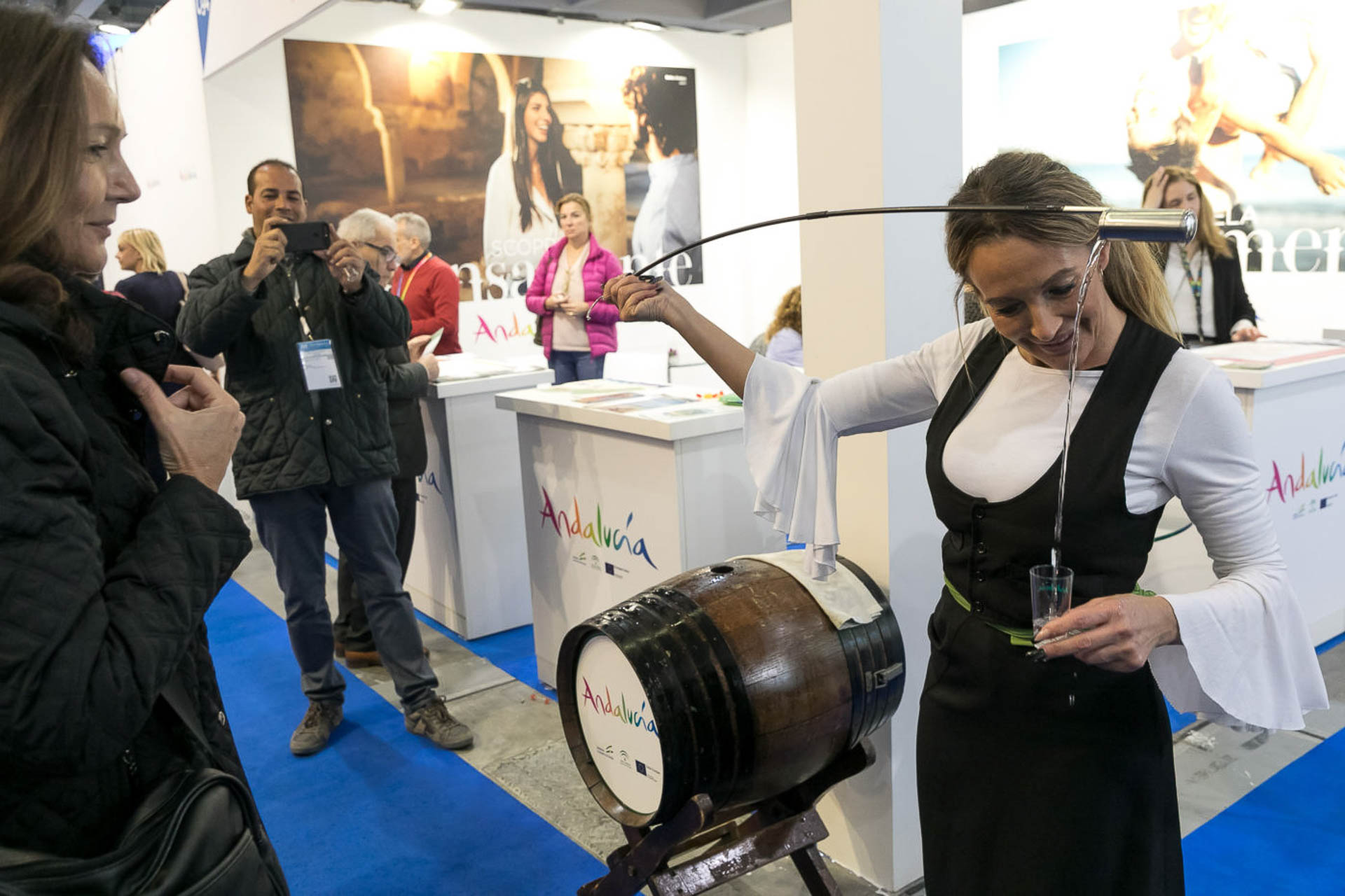 A woman pouring a shot of white liquid from a large stick