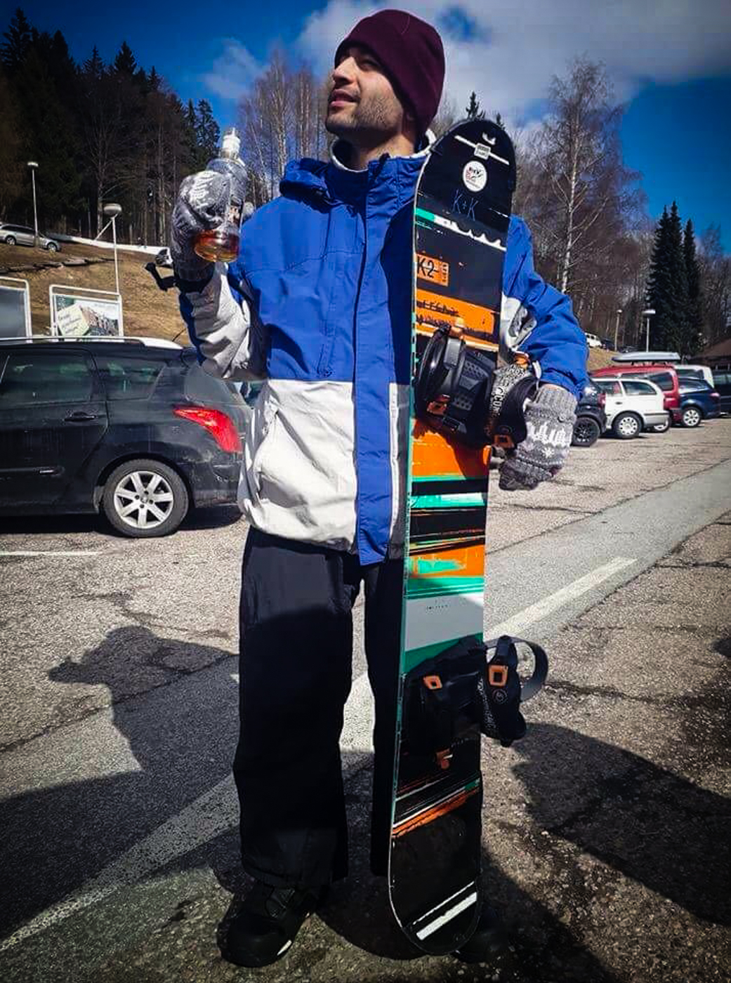 Tiago holding a snowboard and a bottle at the ski area in Czech Republic