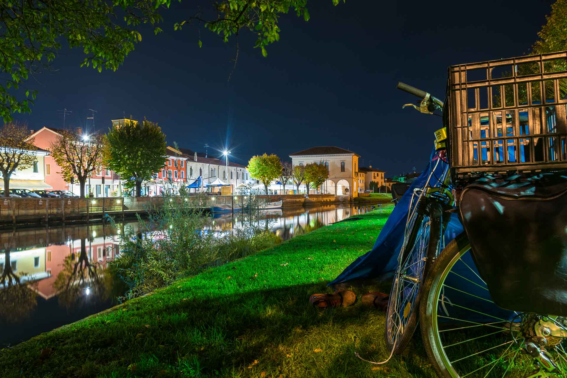 A bike near camping tent by the river at night while cycling in Europe