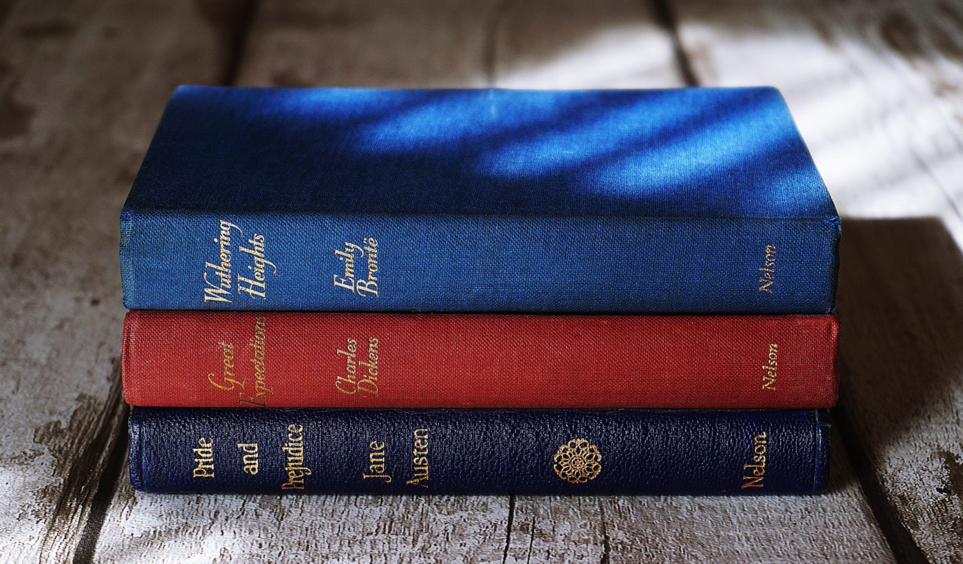 three books piled on top of a wooden table