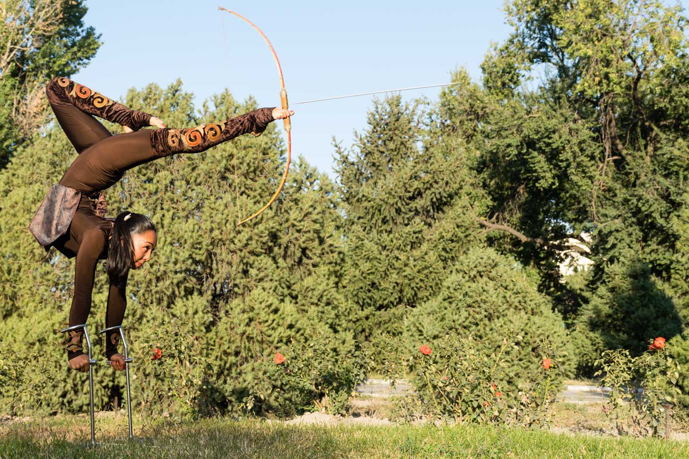 Woman in Kyrgyzstan throwing an arrow with a bow with her feet while handstand