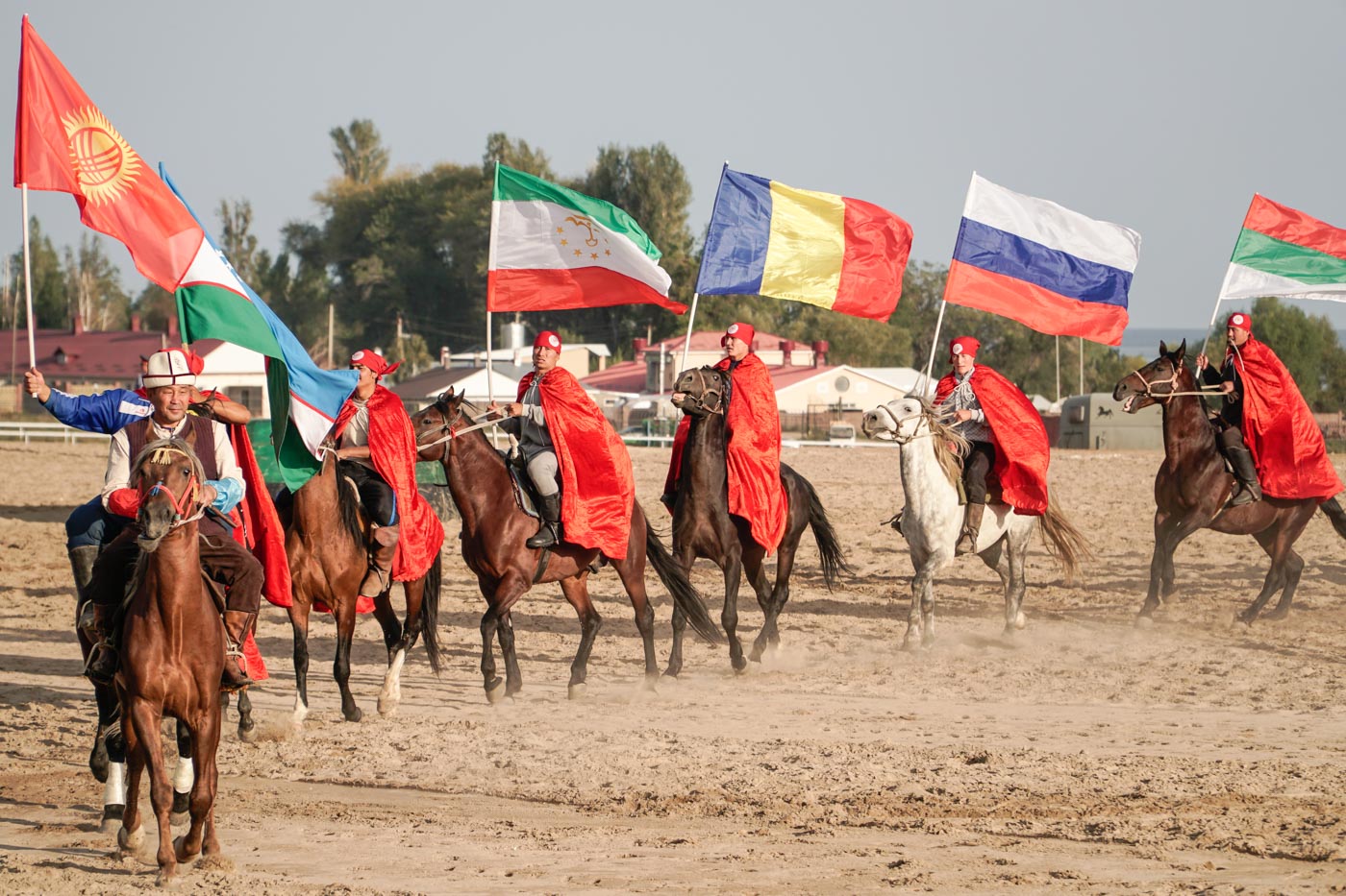 Group of horse men holding many flags from different nations at the world nomads competition