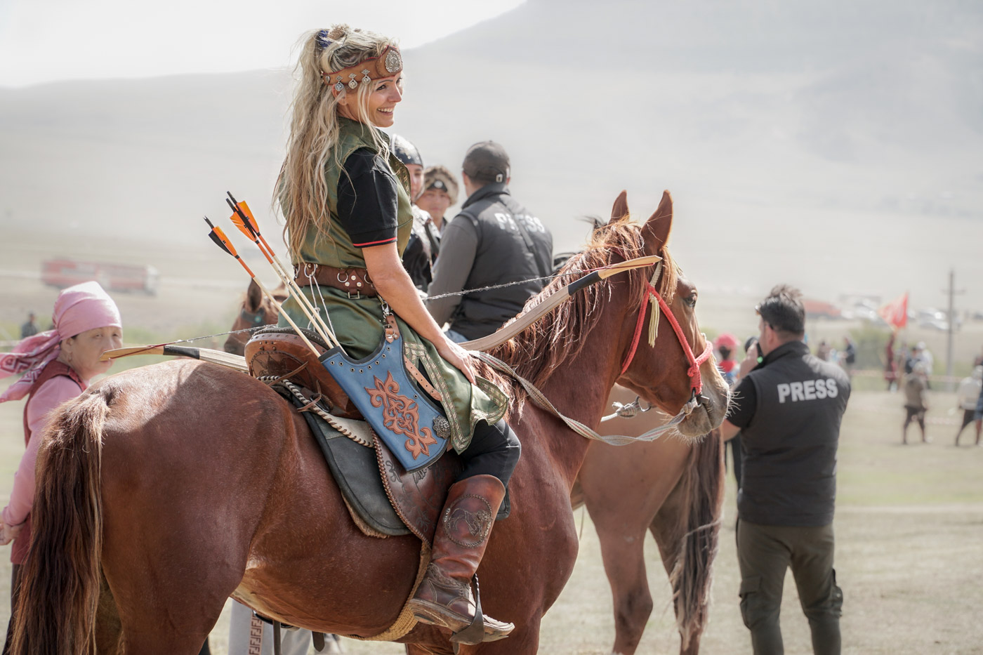 Blond woman smiling on a horse dressed like medieval time