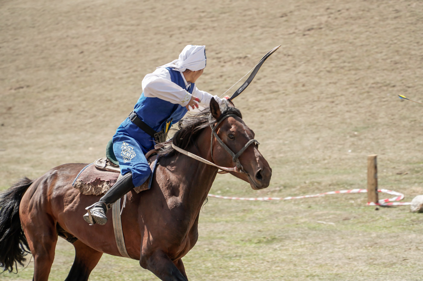 woman archer throwing an arrow while riding a horse