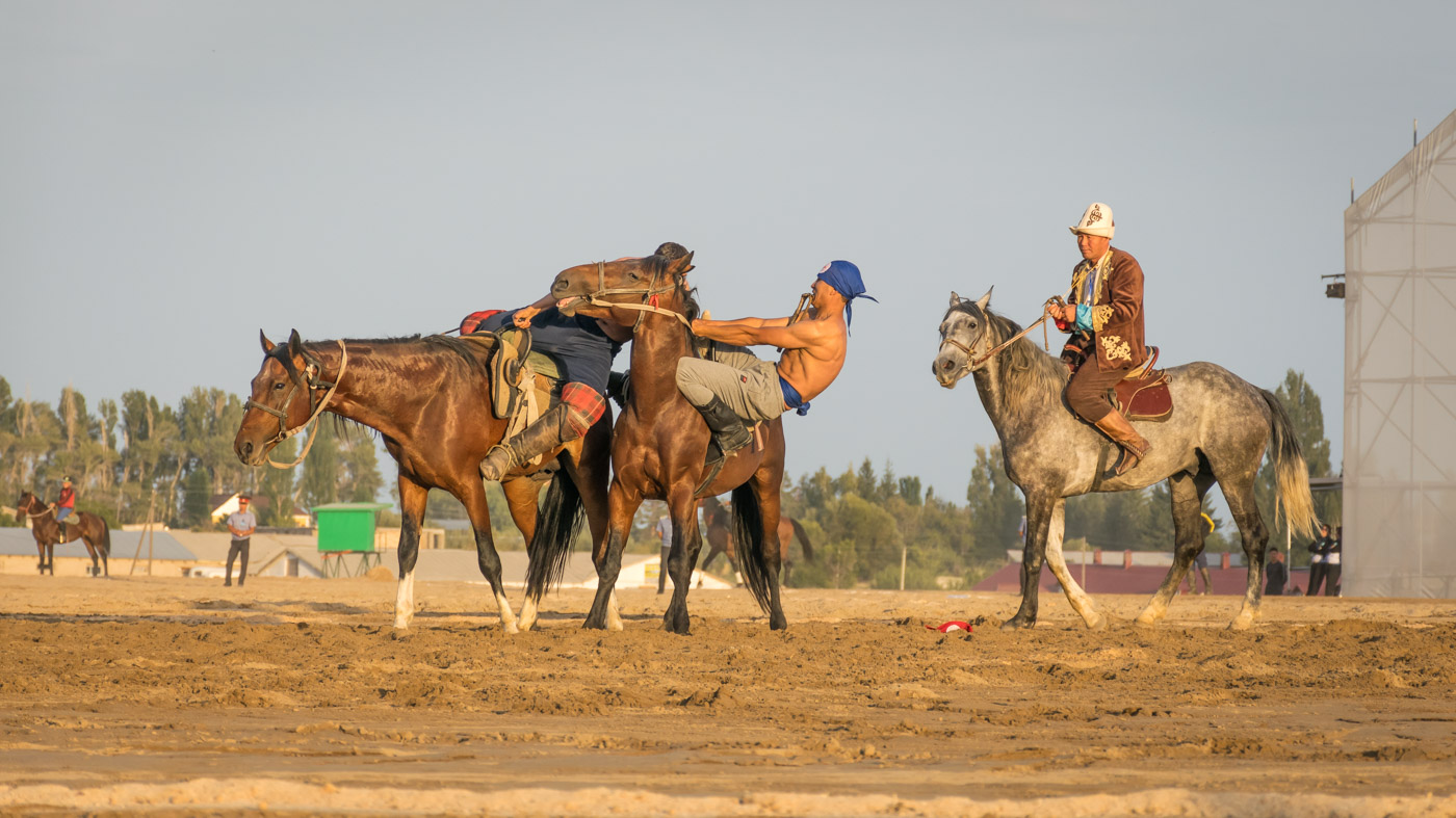 Man pulling another from the top of the horse while wrestling