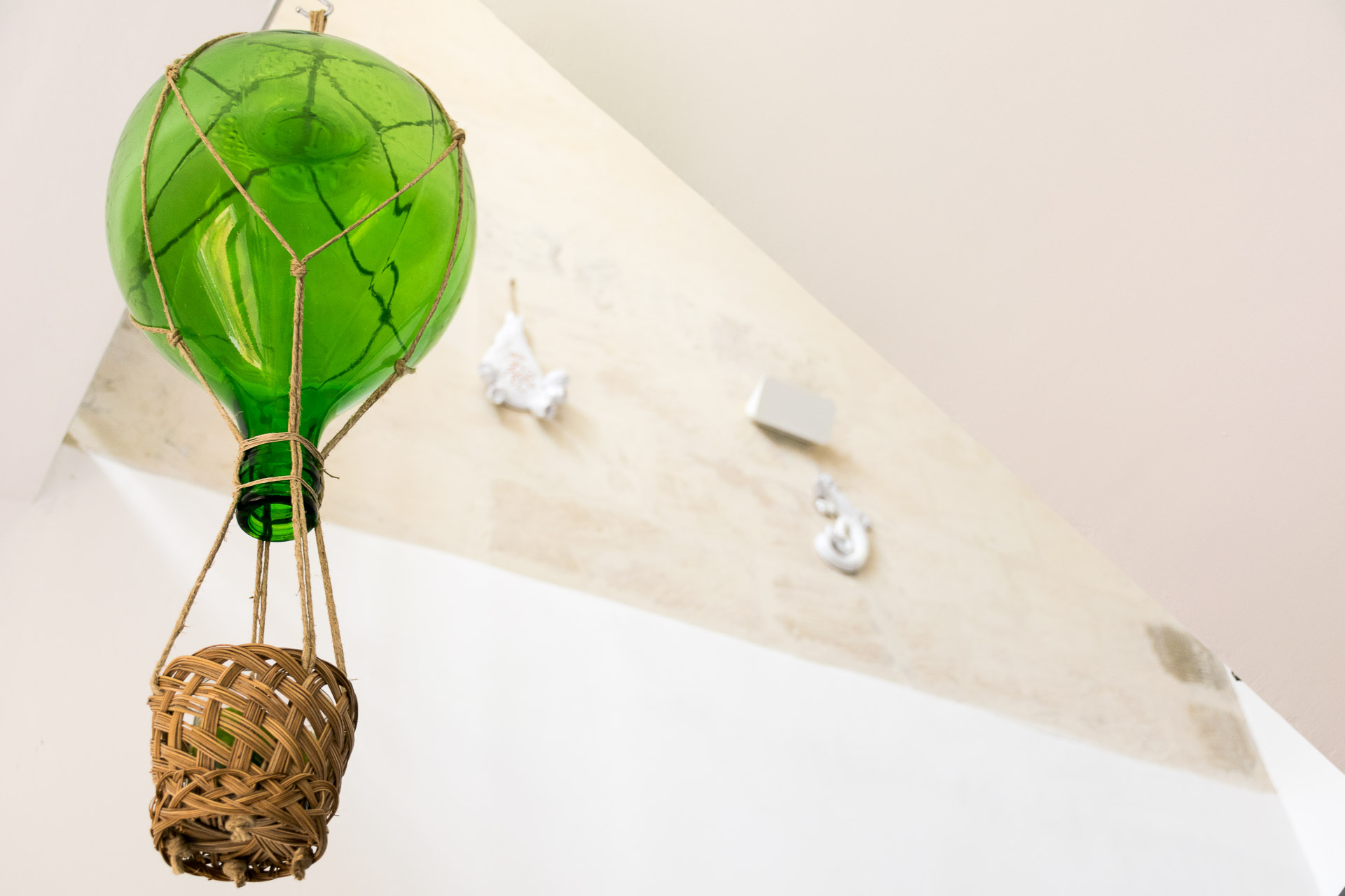 A glass and straw balloon art hanging in a room