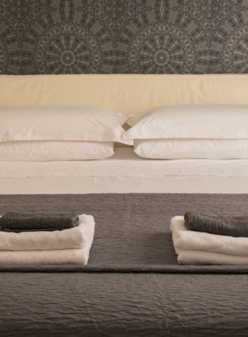 a bed with folded towels on top and warm lights on both bedsides