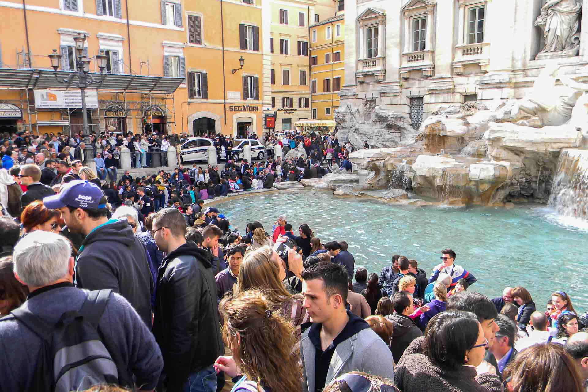 Many people surrounding the Trevi Fountain in Rome