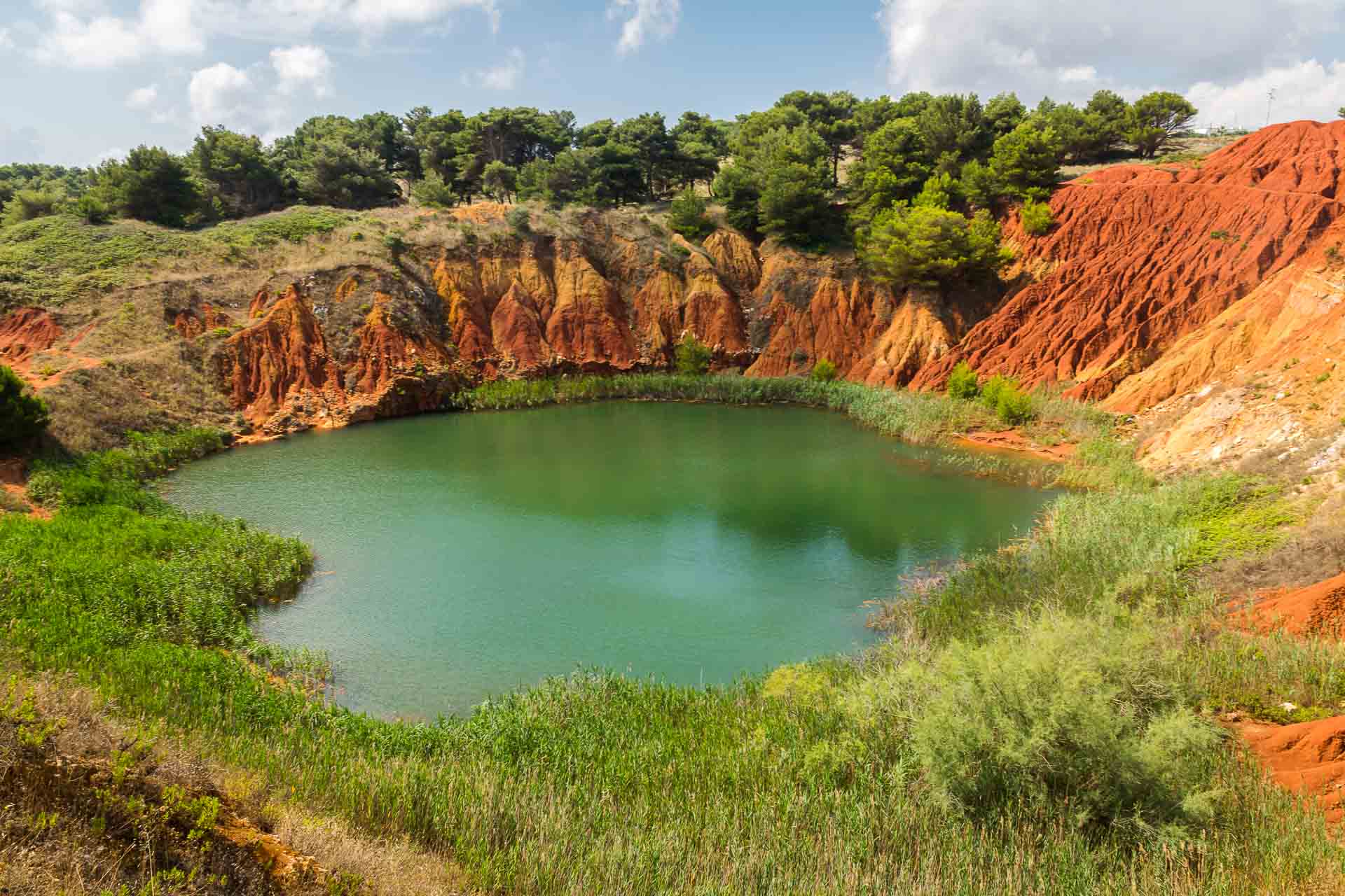 O lago verde emeralda de Bauxita contornado pela terra vermelha