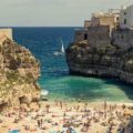 A crowded small beach in between rocks of Polignano A Mare