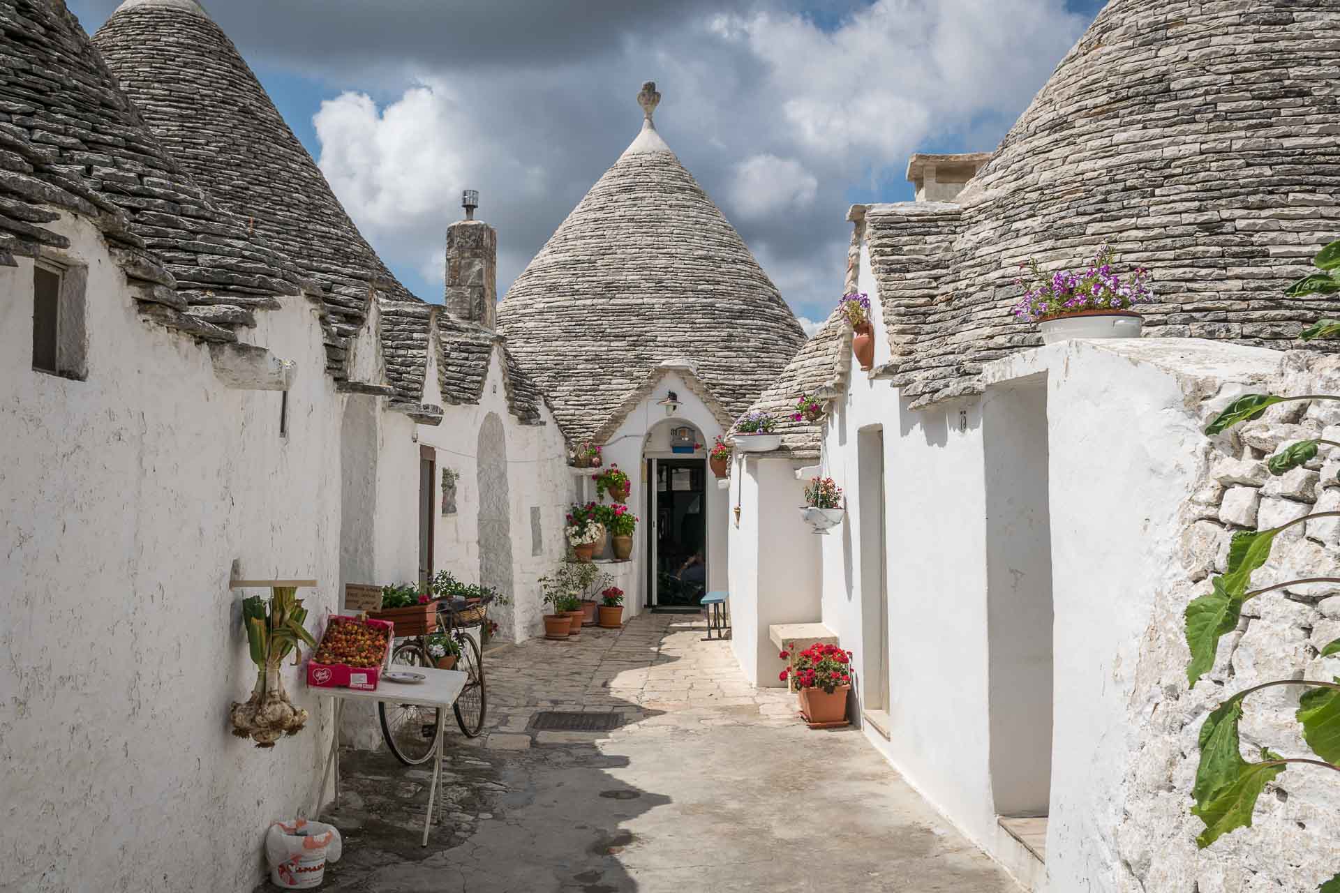 Uma rua sem saída de Alberobello com suas casas típicas e flores na porta