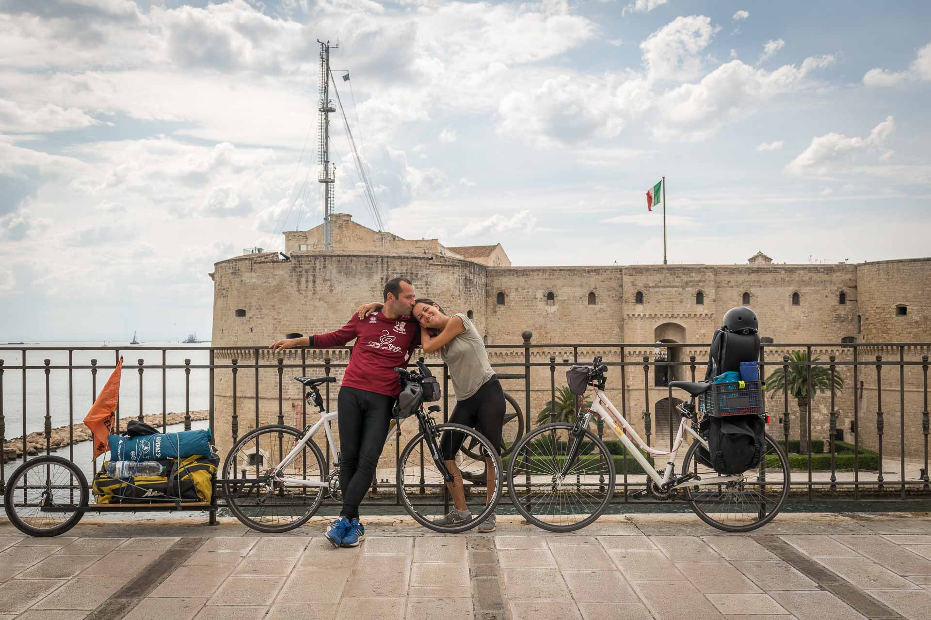 Tiago and Fernanda in front of a castle in Taranto with their bikes