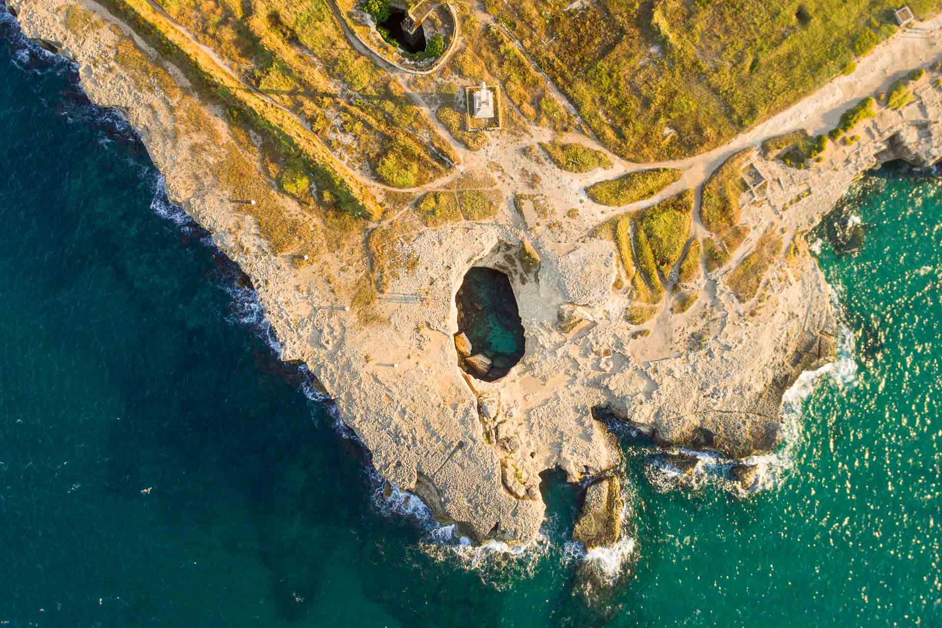Aerial shot of the Grotta della poesia, a hole in the floor surrounded by the sea. A must spot to put in your Puglia itinerary