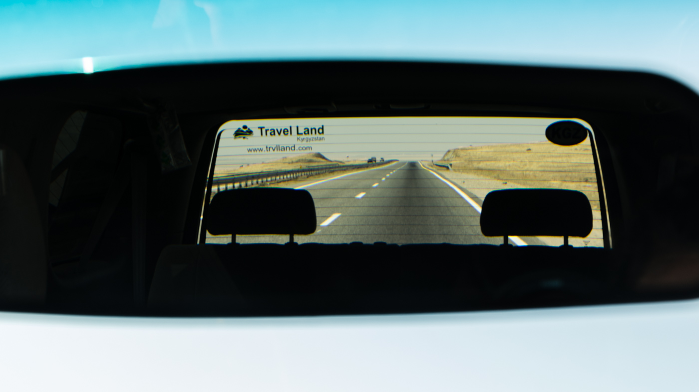 The rear mirror of the car in Kyrgyzstan and the infinite road in the  background