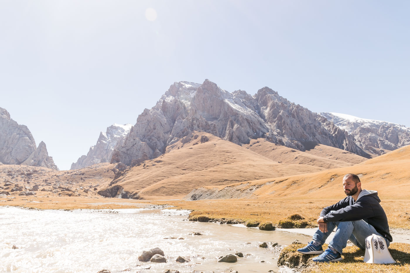 Tiago resting by the lake in Kyrgyzstan surrounded by mountains