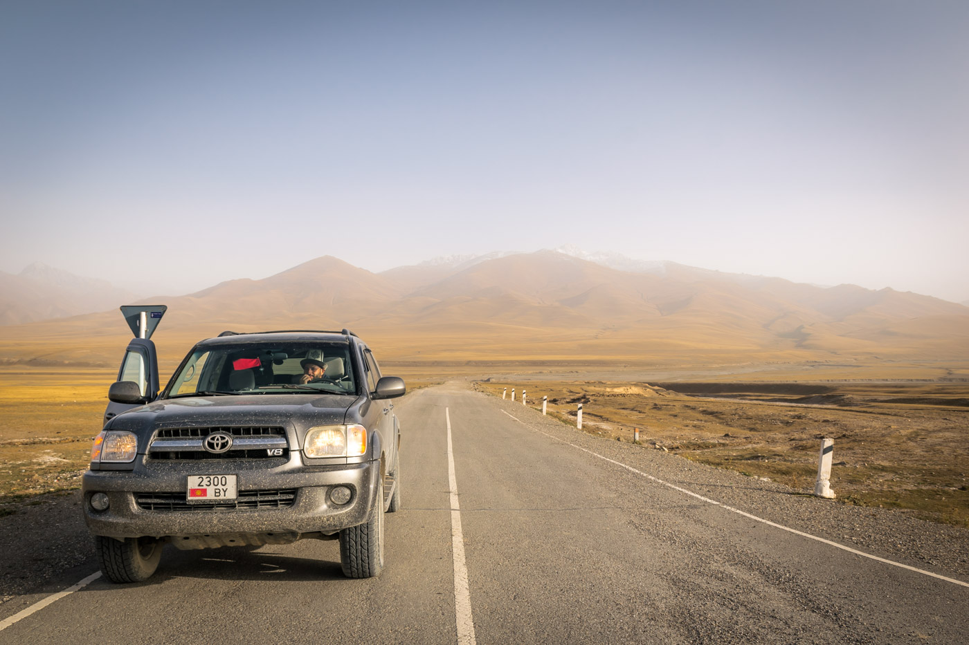 Our car stopped in the side of the road in Kyrgyzstan with a range of mountains in the background