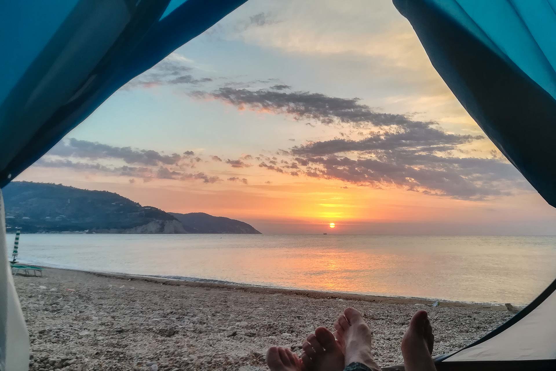 The sun rising from the inside a tent in the Gargano showing our feet