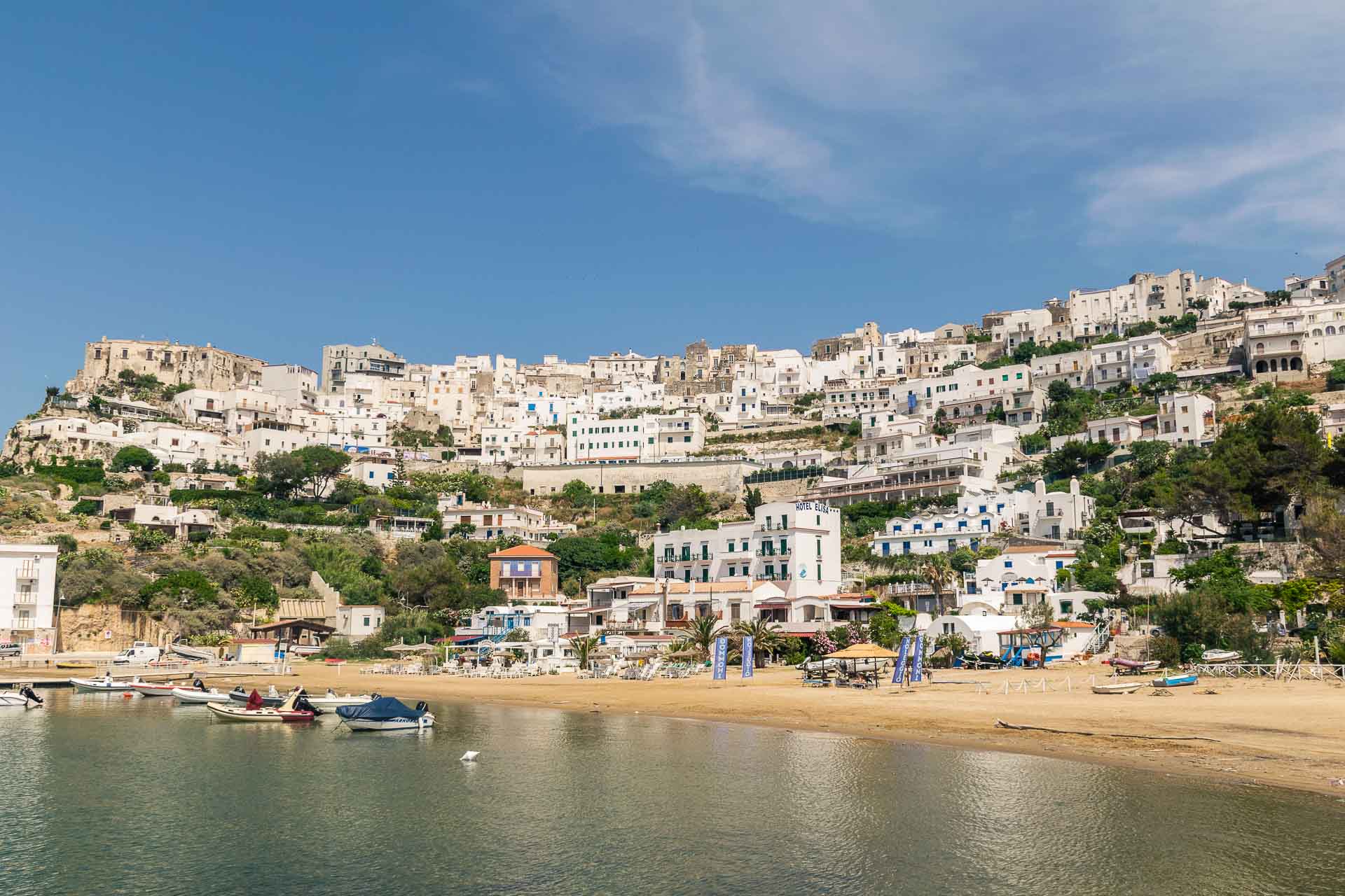 Many houses from bottom to top of a cliff, all white and by the beach of Peschici in Puglia