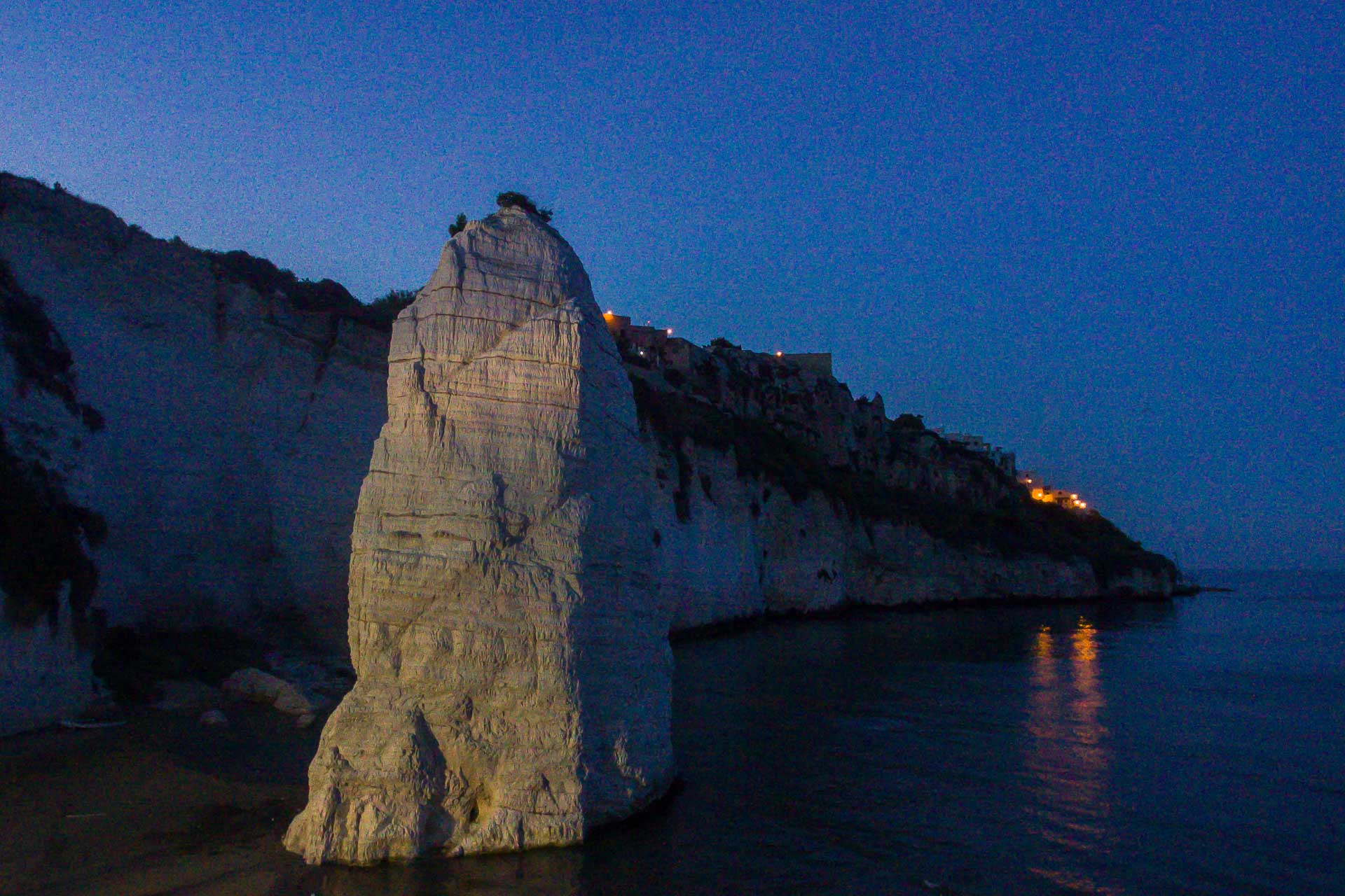 A large rock on the beach near the cliff at night