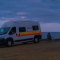 Fernanda sitting on a chair in front of a motorhome watching the full moon on the horizon in Australia